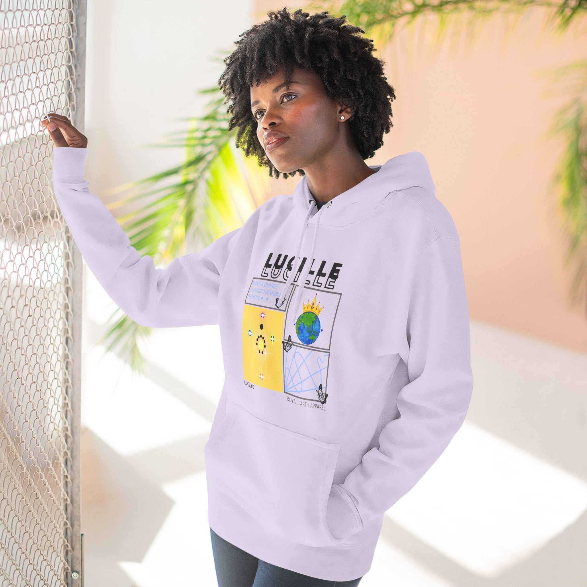 Person wearing a lilac hoodie with a graphic design, standing against a neutral background with plants.