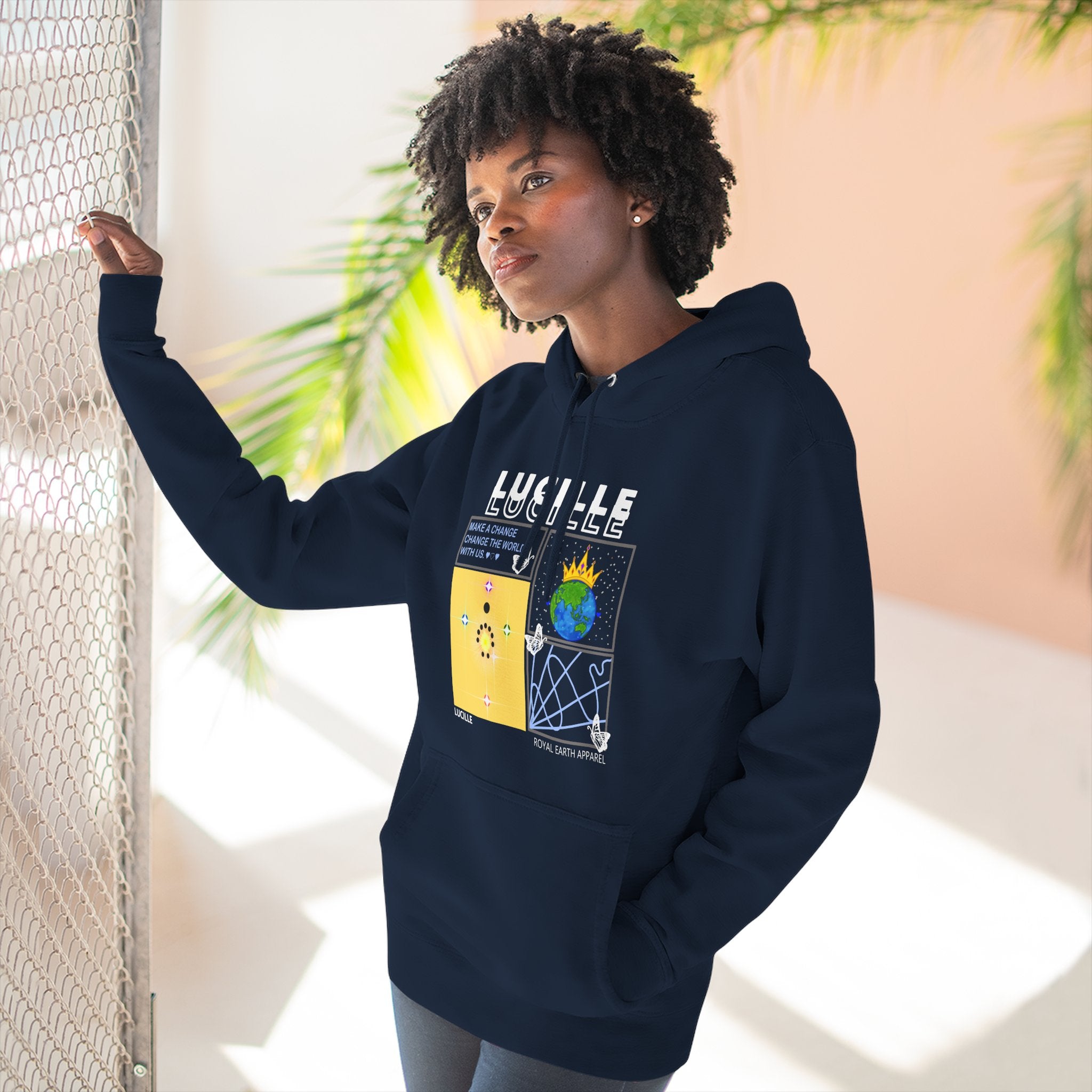 Person wearing a navy blue hoodie with a Lucille graphic design, standing indoors with plants in the background.