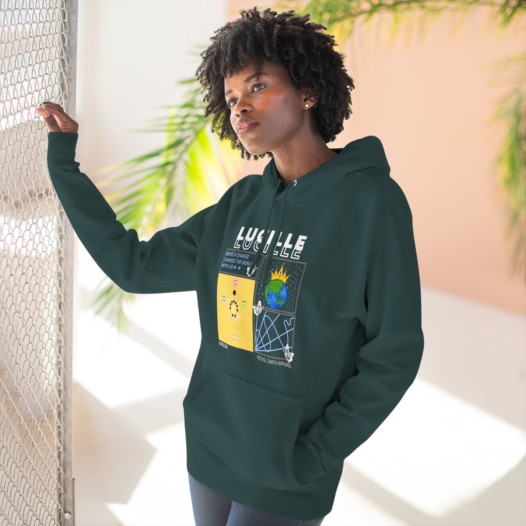 Person wearing a sports green hoodie with a Lucille graphic design, standing indoors with plants in the background.