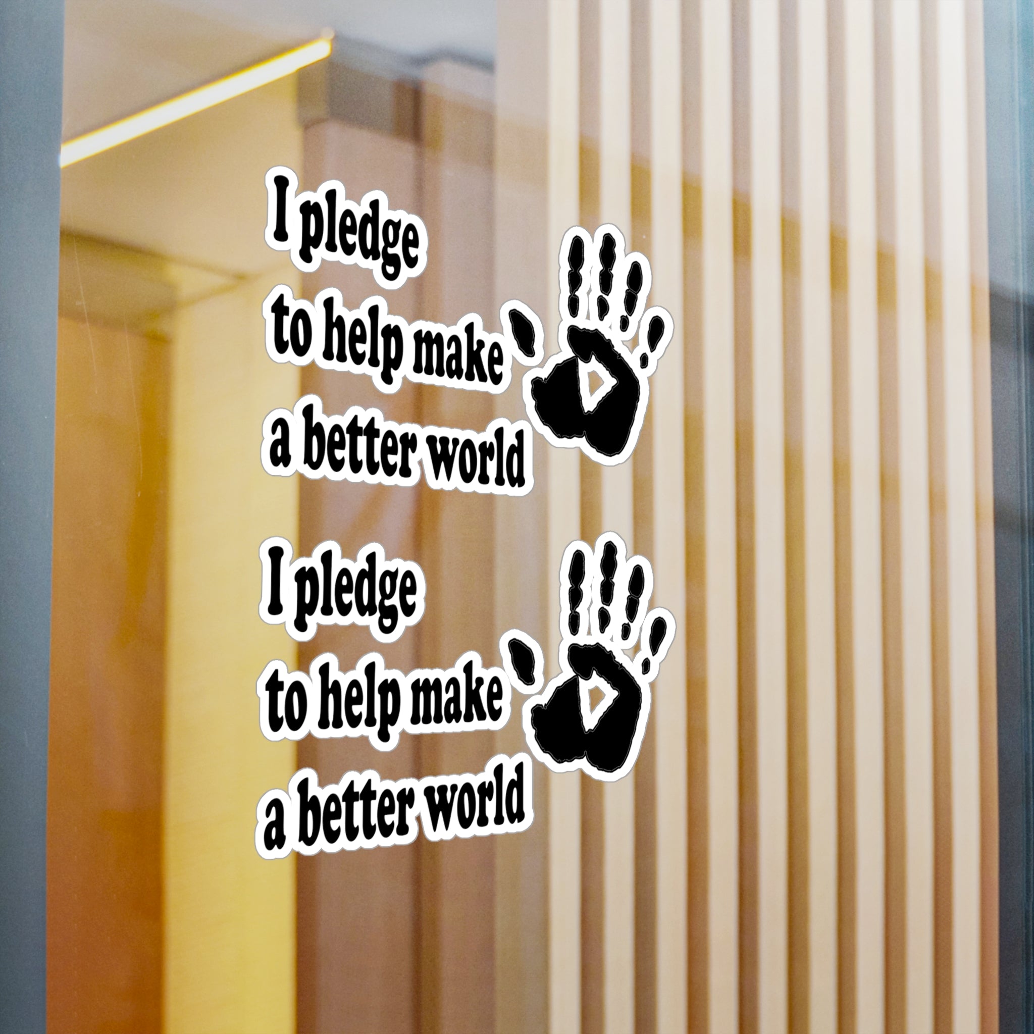 Wall decal with text 'I pledge to help make a better world' and handprints on glass