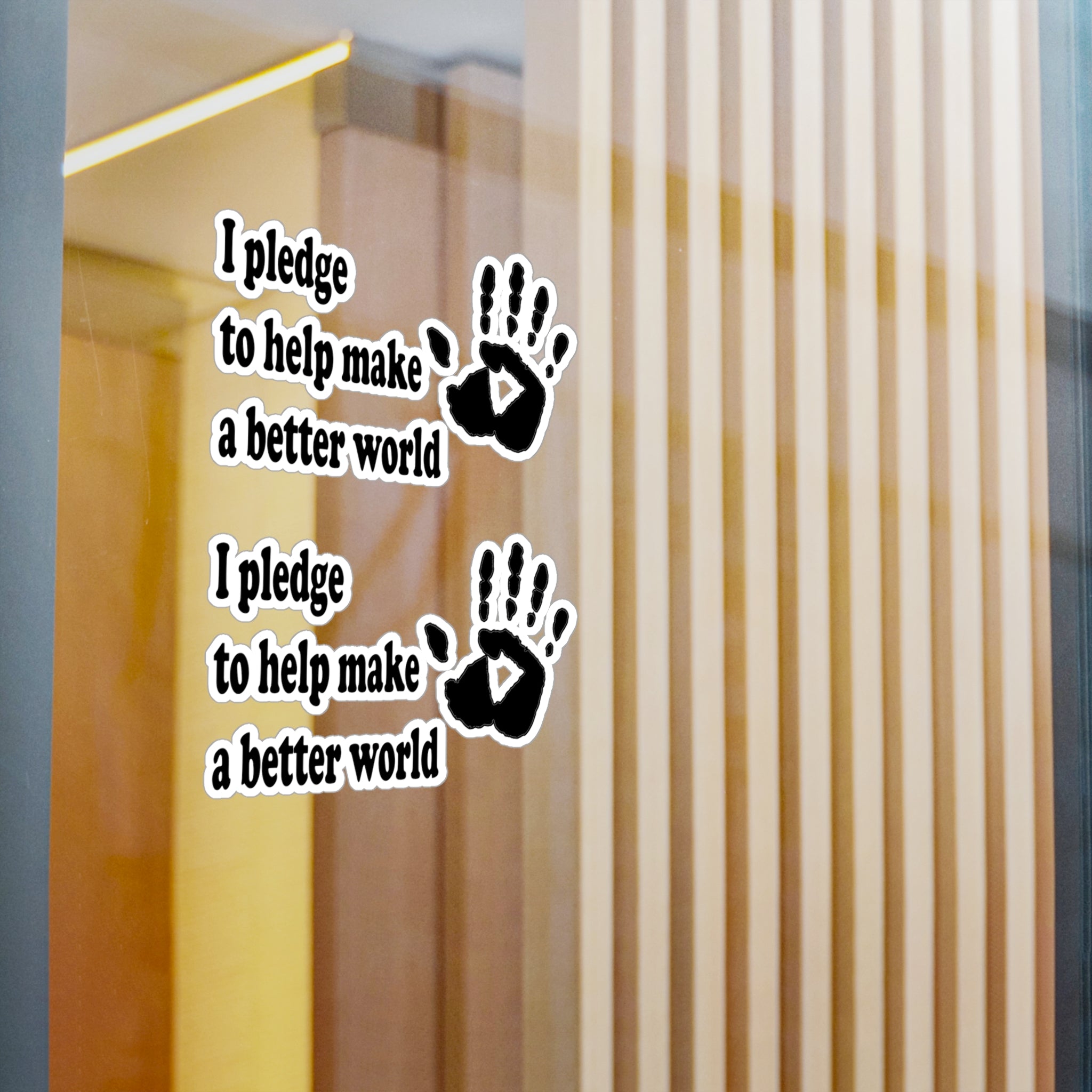 Wall decal with handprints and text 'I pledge to help make a better world' on a glass door